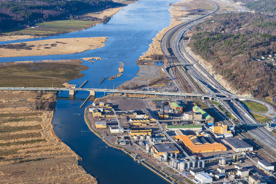 Aerial view of the Bohus industrial area situated along the Gota alv river with a bridge, highway, and railway infrastructure in Ale, Vastra Gotaland County, Sweden.