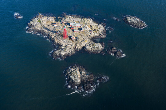 Aerial view of the iconic red Pater Noster lighthouse situated on a rocky island surrounded by deep blue sea in Kladesholmen, Vastra Gotalands lan, Sweden.
