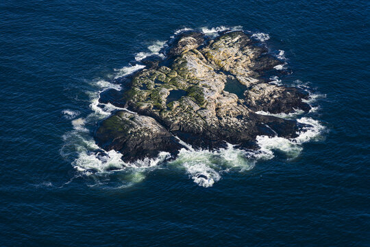 Aerial view of the rocky skerry Pater Noster Skaren surrounded by deep blue sea with white waves crashing against the shore in Kladesholmen, Vastra Gotalands lan, Sweden.