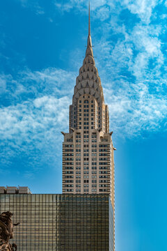 View of the iconic Chrysler Building in midtown Manhattan, displaying its legendary Art Deco architecture, stainless steel terraced crown, spire, and gargoyles against the sky in New York City.