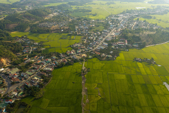 Aerial view of the town of Lien Son Lak nestled beside the expansive Lak Lake, surrounded by lush green rice paddies and rolling hills in Lien Son Lak, Dak Lak, Vietnam.