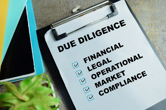 Concept of due diligence write on clipboard isolated on Wooden Table. For financial, legal, operational, market, compliance