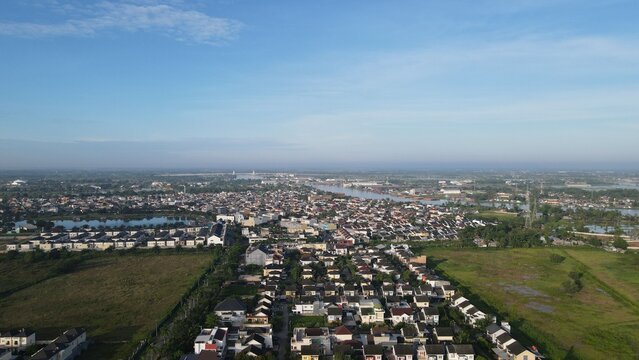 Aerial view of the Jakabaring area featuring dense residential housing, green fields, and a river winding through the landscape in Kecamatan Seberang Ulu I, Sumatera Selatan, Indonesia.