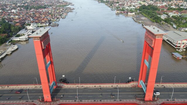 Aerial view of the iconic Ampera Bridge spanning the Musi River with urban development and traffic in the background in Kecamatan Seberang Ulu I, Sumatera Selatan, Indonesia.