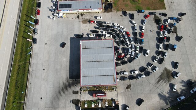Aerial view of Jalan Tol Terbanggi Besar - Pematang Panggang - Kayu Agung rest area with cars parked in rows on the concrete lot in Kecamatan Lempuing Jaya, Sumatera Selatan, Indonesia.