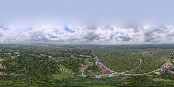 Aerial view of the Tara Bunga area in Tampahan, featuring vast palm oil plantations, winding rural roads, scattered residential houses, and a cloudy sky in Tampahan, North Sumatra, Indonesia.