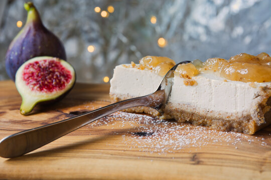 Vegan cheesecake slice cut with spoon served with fresh figs and bokeh lights