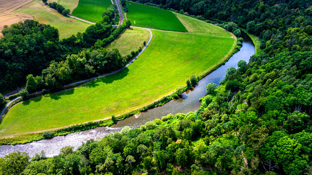 Aerial view of the Lahn river winding through lush green meadows and dense forests in Germany.