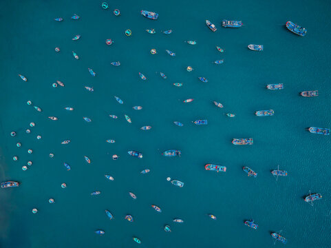 Aerial view of numerous small fishing boats scattered across the deep blue water in Vietnam.