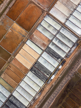 Aerial view of salt pans with rectangular pools showing varying shades of brown and white in Vietnam.