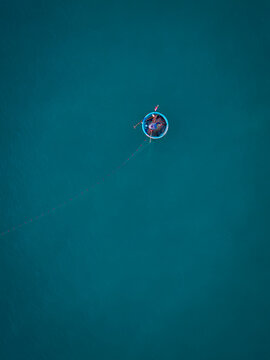 Aerial view of a traditional round basket boat with a fisherman on the calm blue sea in Vietnam.
