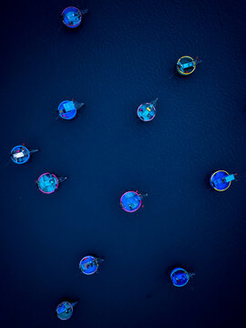 Aerial view of traditional round basket boats floating on dark blue water in Vietnam.