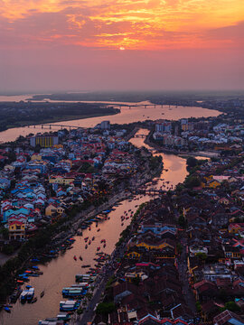 Aerial view of the historic town of Hoi An with traditional boats on the river at sunset, Vietnam.