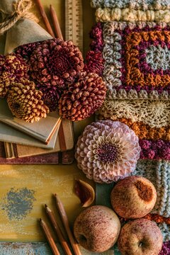 Dark brown and pink dahlias in paper wrap on a yellow chalkboard with apples and notebooks for a warm Teachers Day greeting card