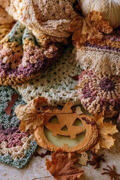 Carved paper pumpkin cutout surrounded by autumn leaves and crochet textiles for a cozy handmade Halloween greeting with copy space