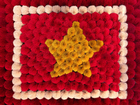 Aerial view of a textured flag of Vietnam crafted from red and yellow pom-poms, creating a soft, tactile surface in Vietnam.