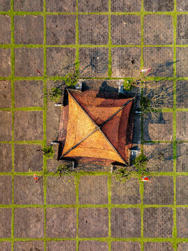 Aerial view of a traditional tiled-roof structure centered within a geometric grid of stone pavers and grass in Vietnam.