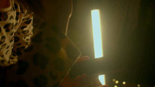 young white girl by lamp night, closeup of child in leopard pajamas touching warm LED tube with string bokeh, hands tracing light, cozy bedtime wonder and quiet imagination scene 