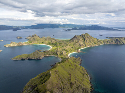 Aerial view of Padar Island with its iconic crescent-shaped beaches, dramatic green hills, and turquoise waters in Komodo, East Nusa Tenggara, Indonesia.