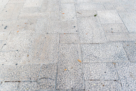 Granite paving stone floor texture with regular rectangular tiles and visible grout lines, outdoor urban walkway surface in neutral gray tones, nobody