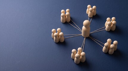 Obraz premium Central wooden human figure linked to various groups of smaller figures via strings on minimalist dark blue background.