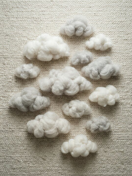 Fluffy cloud shaped forms arranged in a circle on a textured beige rug
