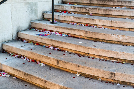 Confetti and flower petals scattered on stone steps after outdoor celebration event, colorful debris covering old concrete staircase with nobody in sight