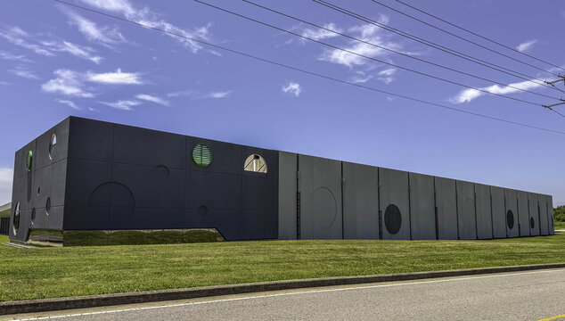 View of the Csquare Data Center featuring modern dark and light grey paneling with circular architectural accents and green vents under a clear blue sky in Gallatin, Tennessee, United States.