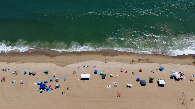 Aerial view of Will Rogers State Beach with colorful umbrellas and people relaxing on the sand by the Pacific Ocean in Los Angeles, California, United States.