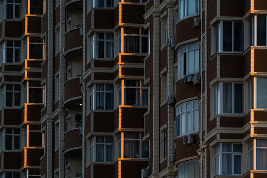 View of the modern apartment building facade with repetitive windows and balconies illuminated by warm golden hour light in Aktau, Mangystau Region, Kazakhstan.