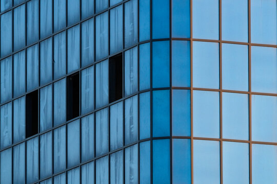View of the modern glass facade of a building with reflective blue panels and dark window frames in Aktau, Mangystau Region, Kazakhstan.