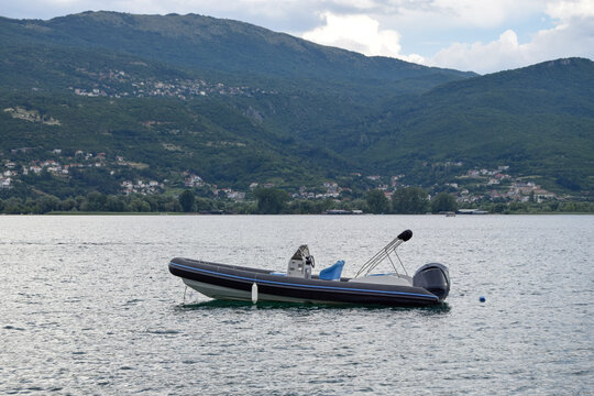 View of a rigid inflatable boat floating on the calm waters of Lake Ohrid with lush green mountains in the background in Ohrid, Municipality of Ohrid, North Macedonia.