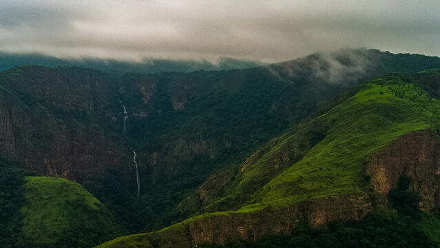 Aerial view of the lush green mountains and a cascading waterfall near Likpe Bakwa, Volta Region, Ghana.