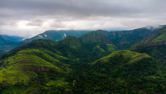 Aerial view of the lush green mountains and rolling hills under a cloudy sky in Likpe Bakwa, Volta Region, Ghana.
