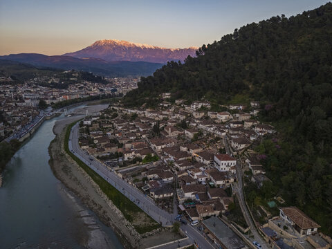 Aerial view of the historic city of Berat with its traditional Ottoman houses, the Osum River, and snow-capped mountains in the background in Berat, Berat County, Albania.