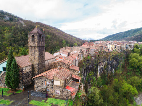 Aerial view of the historic village of Castellfollit de la Roca perched on a basalt cliff with stone buildings and a church tower in Castellfollit de la Roca, Catalunya, Spain.