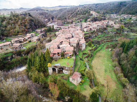 Aerial view of the medieval village of Rupit with its historic stone houses, terracotta rooftops, and lush green surroundings nestled in a valley in Rupit, Catalonia, Spain.