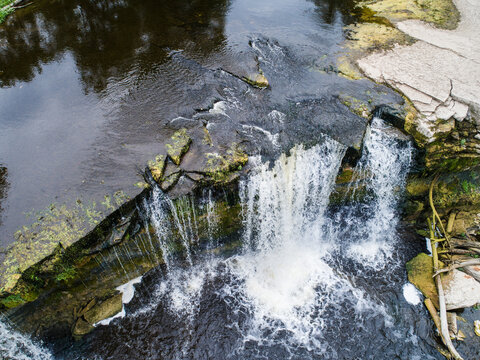 Aerial view of Keila waterfall with cascading water flowing over limestone cliffs into the river below in Meremoisa, Harju maakond, Estonia.