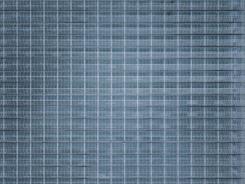 Aerial view of a large industrial greenhouse roof with a repetitive grid structure in Poland.
