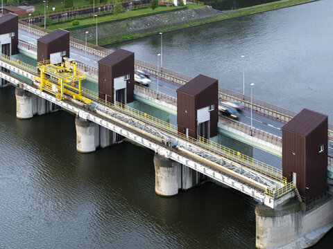 Aerial view of a dam structure with a road bridge crossing the river, featuring concrete piers and brown towers in Krakow, Lesser Poland Voivode, Poland.