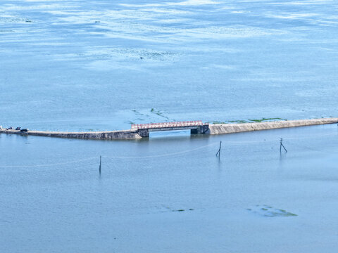 Tahirpur, Sylhet Division, Bangladesh - 04 July 2026: Aerial view of Jadukata River bridge crossing the calm water with a concrete embankment and power lines visible.