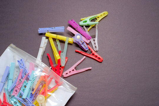 Colorful plastic clothes pegs spilling from bag on dark surface