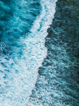 Aerial view of turquoise ocean waves crashing against the shallow reef in Mauritius.