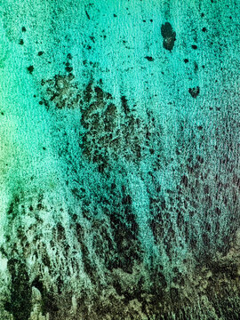 Aerial view of turquoise shallow water with dark coral reef patterns on the seabed in Mauritius.