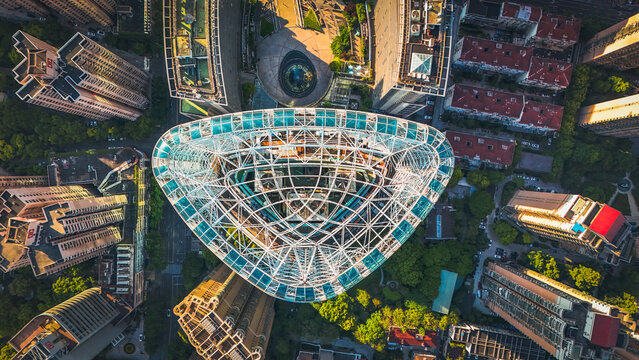 Shanghai, China - 08 May 2024: Aerial view of the Pullman hotel with its unique triangular glass roof, surrounded by high-rise buildings and lush greenery in the city center.