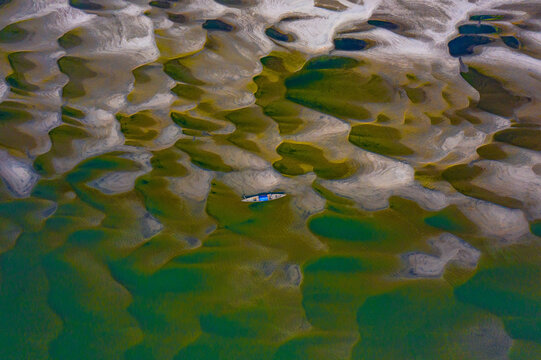 Bogura, Bangladesh - 03 January 2022: Aerial view of a small boat resting on the intricate sandbanks and shallow waters of the Jamuna River near Sariakandi.