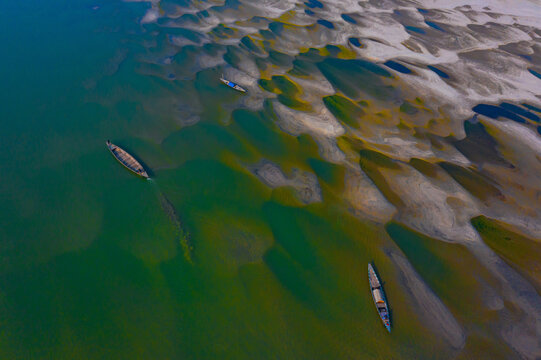 Bogura, Rajshahi Division, Bangladesh - 03 January 2022: Aerial view of Sariakandi sandbars and traditional wooden boats navigating the shallow waters of the Jamuna River.