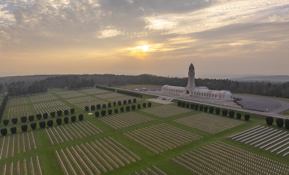 Aerial view of the Douaumont Ossuary and the vast military cemetery at sunset, with rows of white crosses stretching across the green landscape in Douaumont-Vaux, Grand Est, France.
