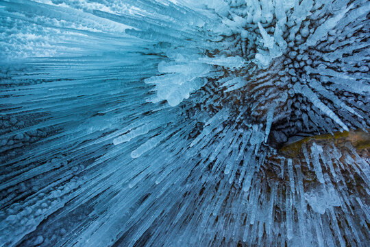 View of intricate blue icicles hanging from the rocky ceiling of a cave at Lake Baikal, Khuzhir, Irkutsk Oblast, Russia.