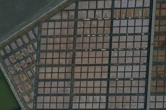 Aerial view of the Salt Museum Salinas del Carmen, featuring a geometric grid of salt pans with varying water levels and textures in Antigua, Canarias, Spain.